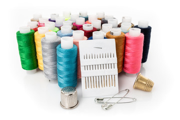 Tailor needles and threads over white.