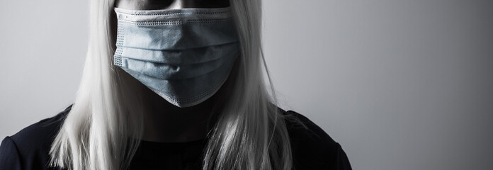 Young long-haired woman in protective medical mask
