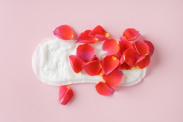 red rose flower petals on scented menstruation pad isolated on pastel pink background, flat layout, top view, intimate hygiene