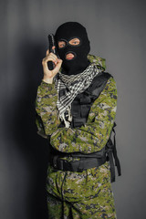 A member of the special police squad, takes aim, holds a pistol. Dressed in a balaclava,  camouflage uniform, bulletproof vest. Special weapons and tactics. Special Forces.SWAT.