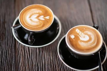 wooden table top with office supplies,cups of cappuccino with latte art on wooden background.working in coffee shop concept.