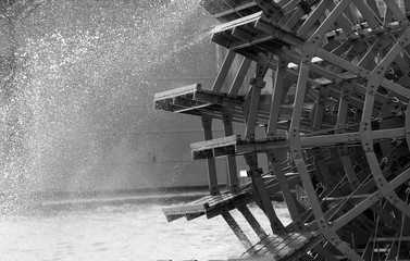 black and white close up of an old paddle wheel on the river