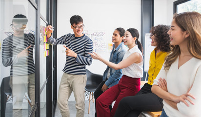 Asian business people meeting conference and brainstorming in modern office, writing on sticky note on glass wall