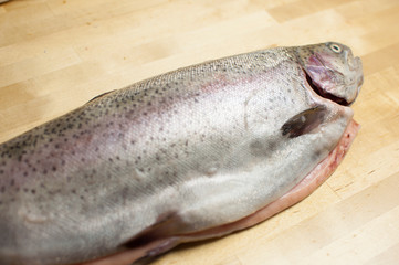 Cutting gutted red fish trout sweetfish on wood background