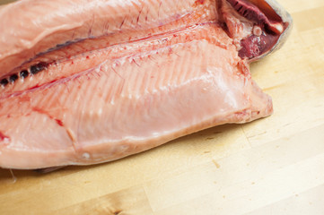 Cutting gutted red fish trout sweetfish on wood background