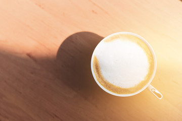 Close-up coffee latte art in cup and milk froth above to drink on wooden table background in the morning.