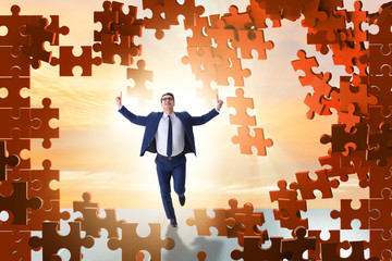 Businessman breaking the wall of jigsaw puzzle