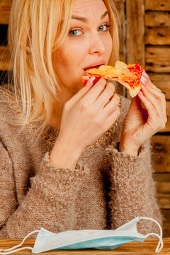 Keep calm and bon appetit! Young bold beautiful woman eating pizza without medicine respirator mask. Vertical image.