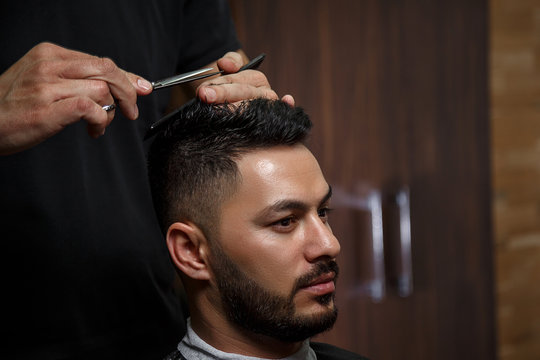 the guy is a dark-haired Asian Indian appearance on a haircut in a barbershop . cinematic image