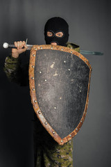 Modern warrior with medieval weapons in his hands. A soldier defends himself with a shield and...