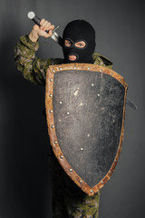 Modern warrior with medieval weapons in his hands. A soldier defends himself with a shield and...