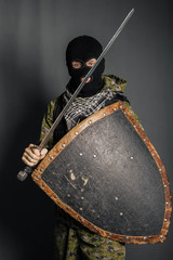 Modern warrior with medieval weapons in his hands. A soldier defends himself with a shield and...