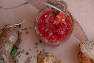 Homemade sausages on paper with mustard and tomato sauce. Cutlery and bread. Top view on a wooden background. Hands holding cutlery.