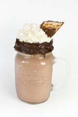 Chocolate cocktail with whipped cream and a nut bar, and with foam in a glass on a white background