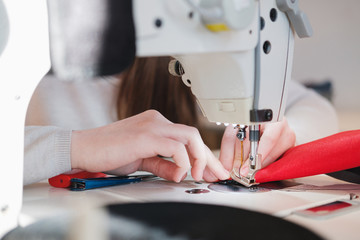 Seamstress hands doing precise work. Needlewoman at overlock sewing machine doing professional...