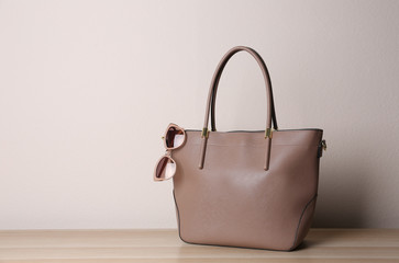 Stylish leather woman's bag on wooden table. Space for text