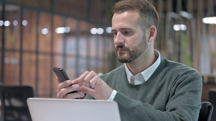 Close Up Shoot of Young Man using Smartphone and Computer