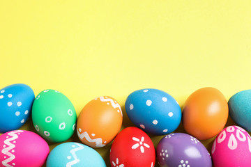 Colorful Easter eggs on yellow background, flat lay. Space for text