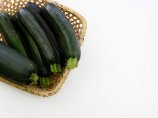 young green zucchini in a wicker basket on a white background