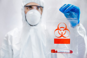 Man in protective goggles and protective costume holds packet for transportation biohazard...