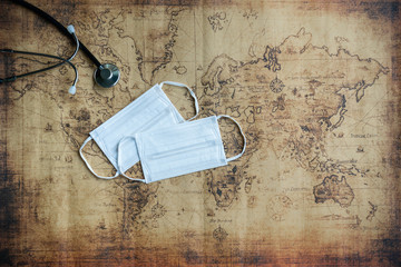 Top view of medical stethoscope and protective face mask on world map background. Prevent pollution and disease concept.