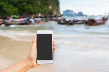 Close up of woman hand holding mobile phone at the sea. Copy space