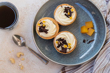 homemade shortbread tartlets or cupcakes with delicate cream and orange jam, decorated with chocolate chips. natural sweets concept. cozy tea party