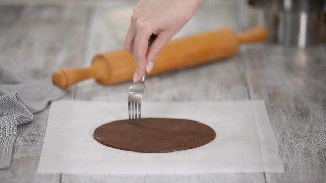 Woman Pierces Dough With A Fork Over To Prevent Air Bubbles While Baking.
