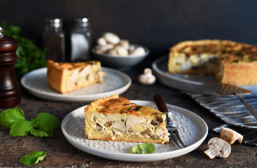 Tart slice on the kitchen table. Traditional quiche with chicken, mushrooms and cheese on a dark concrete background.