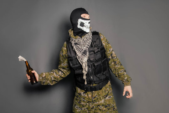 A Man In A Balaclava With A Skull Pattern, Dressed In Camouflage With A Hood And A Bulletproof Vest, Is Holding A Molotov Cocktail In His Hands. A Protester Throws A Molotov Cocktail. Studio Photo On 