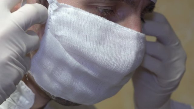 doctor Puting  his mask,closeup doctor puts white mask on face, surgeon prepares for surgery