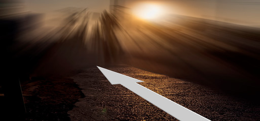 Creative shot of a white-colored arrow on roads leading somewhere in the infinity during sunset/sunrise time with dramatic colors.