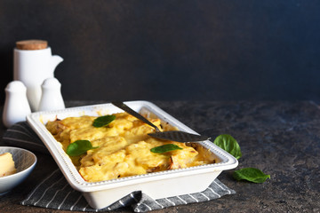 Casserole with potatoes, mushrooms and cheese on the kitchen table. Horizontal focus.