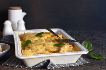 Casserole with potatoes, mushrooms and cheese on the kitchen table. Horizontal focus.