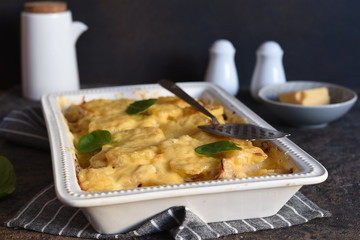 Casserole with potatoes, mushrooms and cheese on the kitchen table. Horizontal focus.