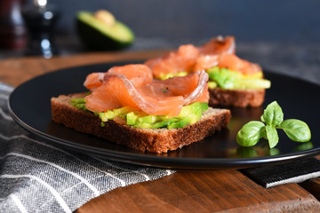 Sandwich with avocado and salmon for breakfast on the kitchen table.