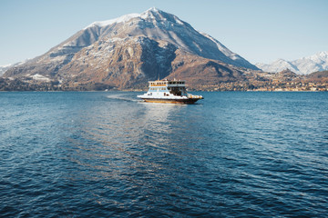 Passenger ship crossing Lago di Como, Italy. Sunny snowy mountain landscape background