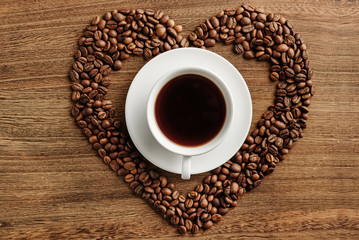 Composition with a cup of coffee in the center of a heart-shaped coffee bean