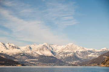 Fototapeta na wymiar Panoramic of snowy mountain reflected in Lago di Como in Italy, clear and sunny sky. Rule of thirds
