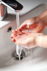 woman washing hands with antibacterial soap under running water
