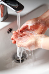woman washing hands with antibacterial soap under running water