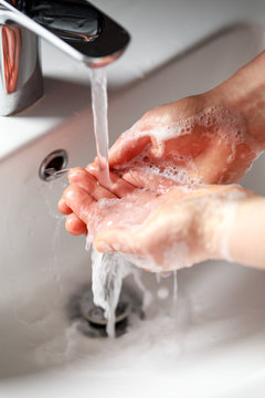 woman washing hands with antibacterial soap under running water