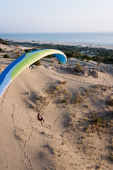 Fototapeta na wymiar Paragliding on the sand dunes during sunset. Beautiful golden sand.