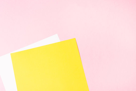 White and yellow blank paper on pink background. Empty free space. background. 