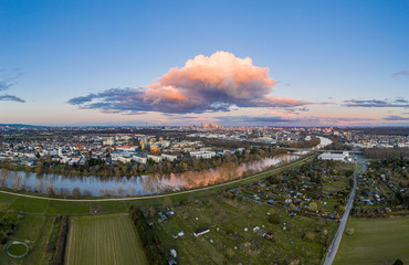 Aerial panoramic picture of river Main and the Frankfurt skyline during sunset in afterglow with illuminated cloud