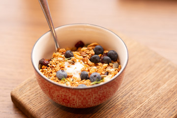 Homemade granola bowl with greek yogurt and blueberries on brown background, top view. Healthy energy breakfast or snack