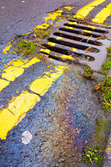 Obraz premium Petrol Gasoline Oil Spill on The Road Tarmac Rainbow Colour Pollution Running Down a Drain