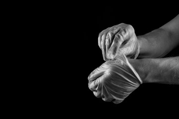 Man taking off medical rubber gloves , isolated on black background copy space