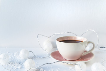Retro cup of coffee on white background with snow and christmas lights
