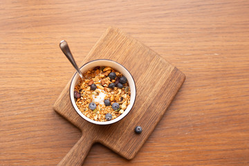 Top view Homemade granola bowl with greek yogurt and blueberries on brown background, Healthy energy breakfast or snack